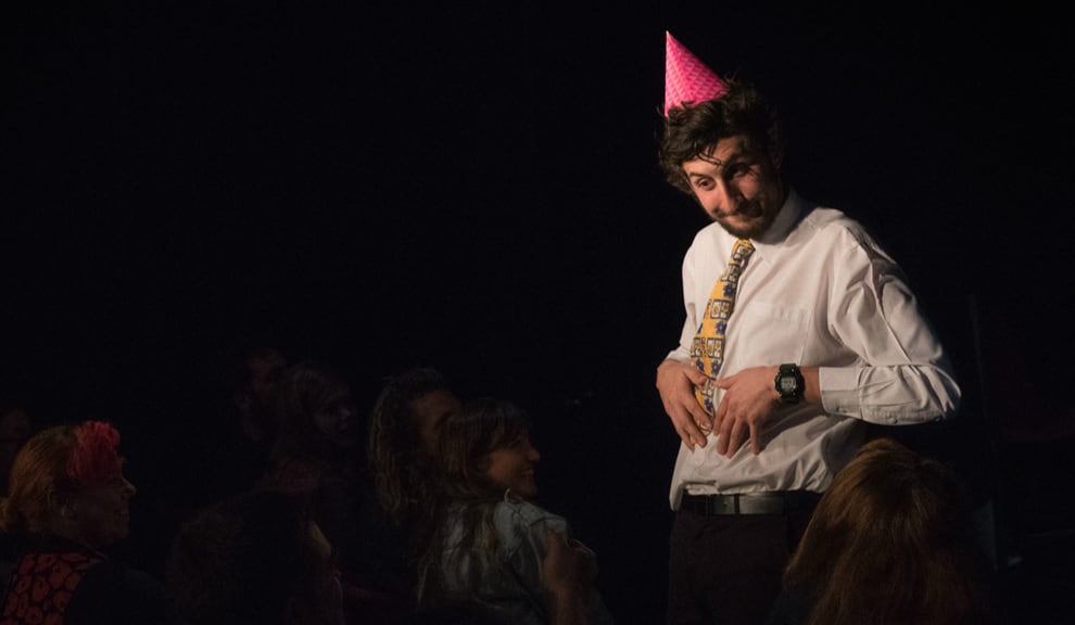 photo: Jeromaia looks quizzically at the audience, wearing a pink party hat