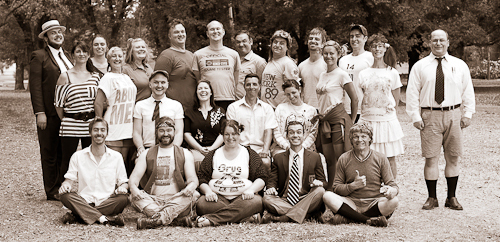 The entire Impro Melbourne performance company poses in vintage school clothes for a class photo.